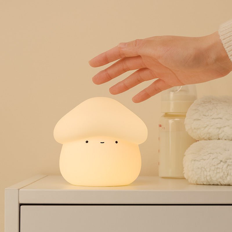 Mushroom-shaped night light being touched by a hand on a neutral background
