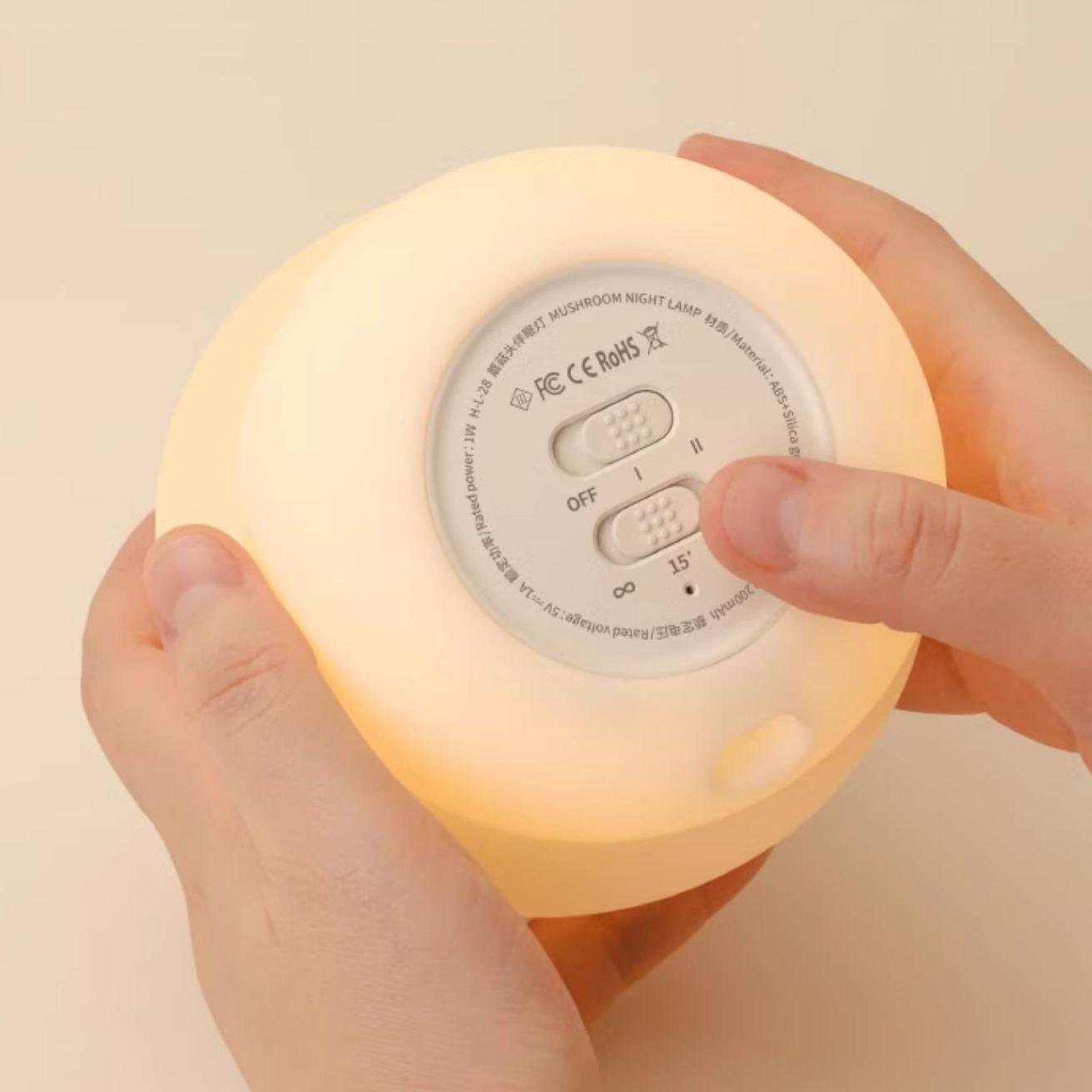 Hand holding a round night light with control buttons on a beige background
