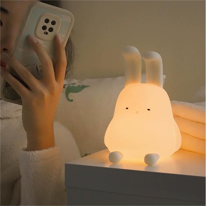 Adorable foldable ear bunny night light with soft silicone body, warm LED glow, tap control, phone stand & hanging function. Rechargeable & portable.