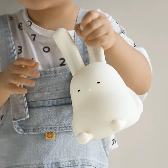Adorable foldable ear bunny night light with soft silicone body, warm LED glow, tap control, phone stand & hanging function. Rechargeable & portable.