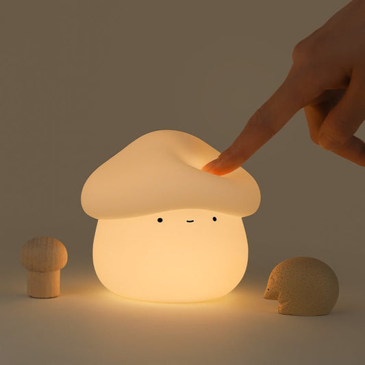 Mushroom-shaped night light with a hand touching it on a dark background