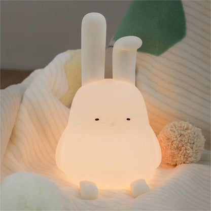 Adorable foldable ear bunny night light with soft silicone body, warm LED glow, tap control, phone stand & hanging function. Rechargeable & portable.